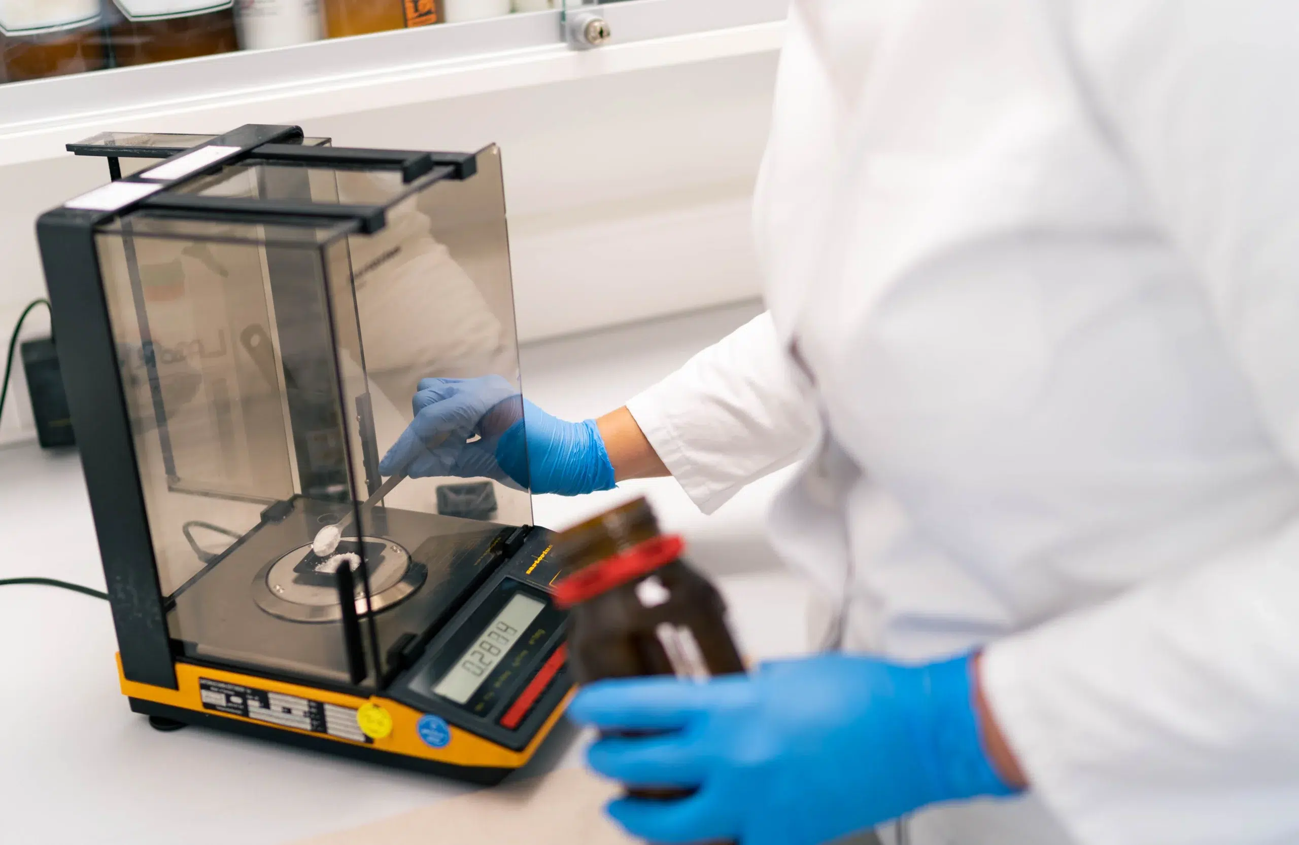 Detailaufnahme im Labor der Gondermann Apotheken: Mitarbeiterin wiegt Pulver in staubfreier Spezialwaage zur Herstellung patientenindividueller Rezepturen – präzise pharmazeutische Arbeit für maßgeschneiderte Arzneimittel