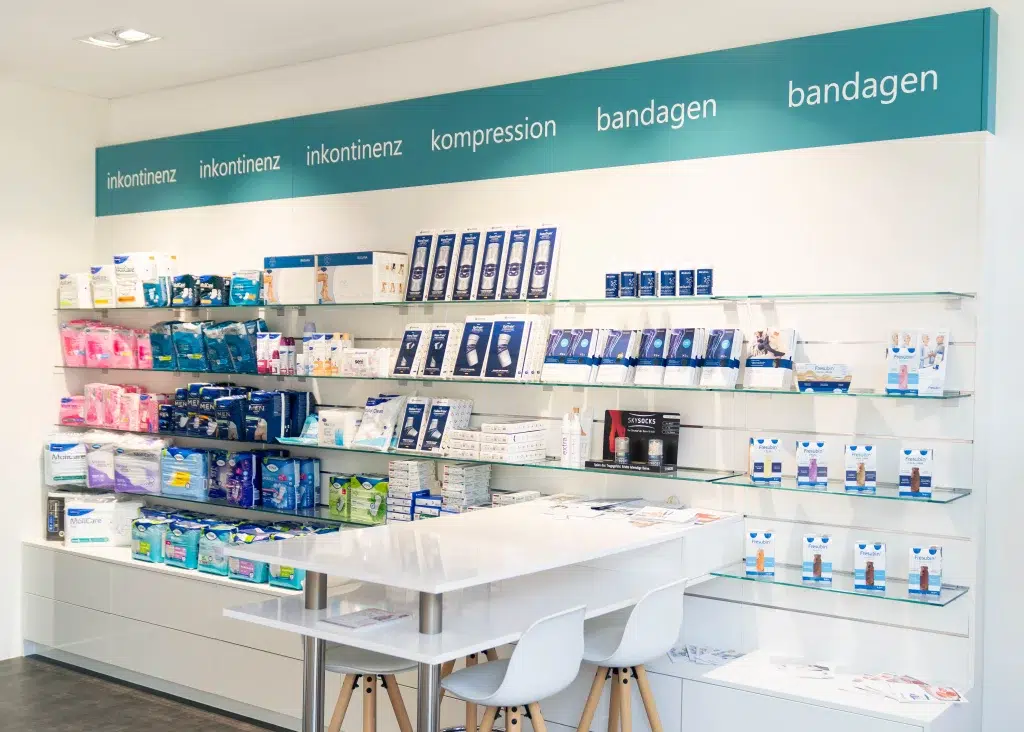 Regal im Lilienpflegeshop der Gondermann Apotheken mit Inkontinenzprodukten, Kompressionsartikeln und Bandagen – davor ein Beratungstisch für persönliche Fachberatung rund um Pflege und medizinische Hilfsmittel in Friedrichsdorf
