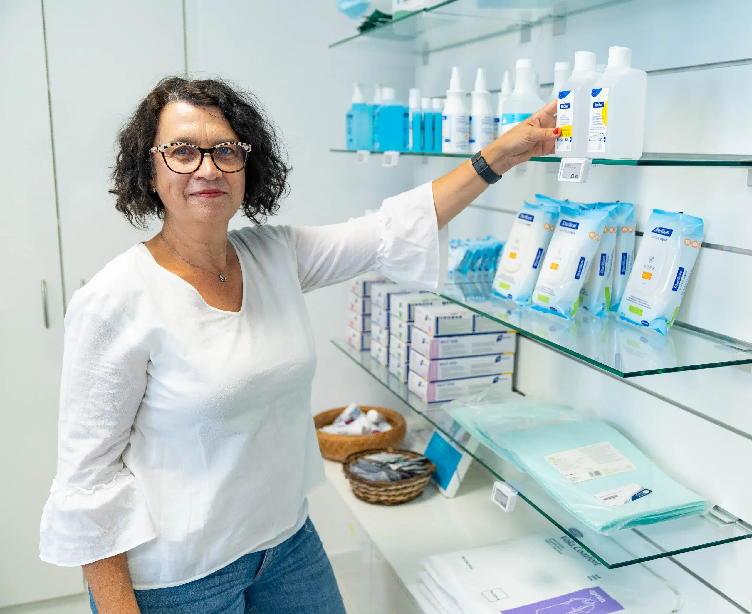 Verkäuferin im Pflegeshop steht beratend vor einem Regal mit Pflegeprodukten – freundliche Atmosphäre und Fokus auf Kundenservice.